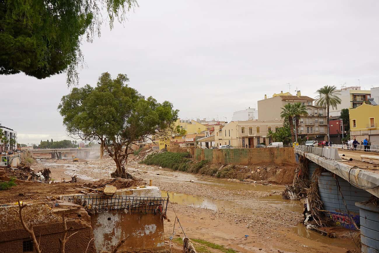 Vue d'une zone inondée à Valence avec un pont endommagé, des eaux boueuses et des bâtiments endommagés, illustrant la gravité des inondations.
