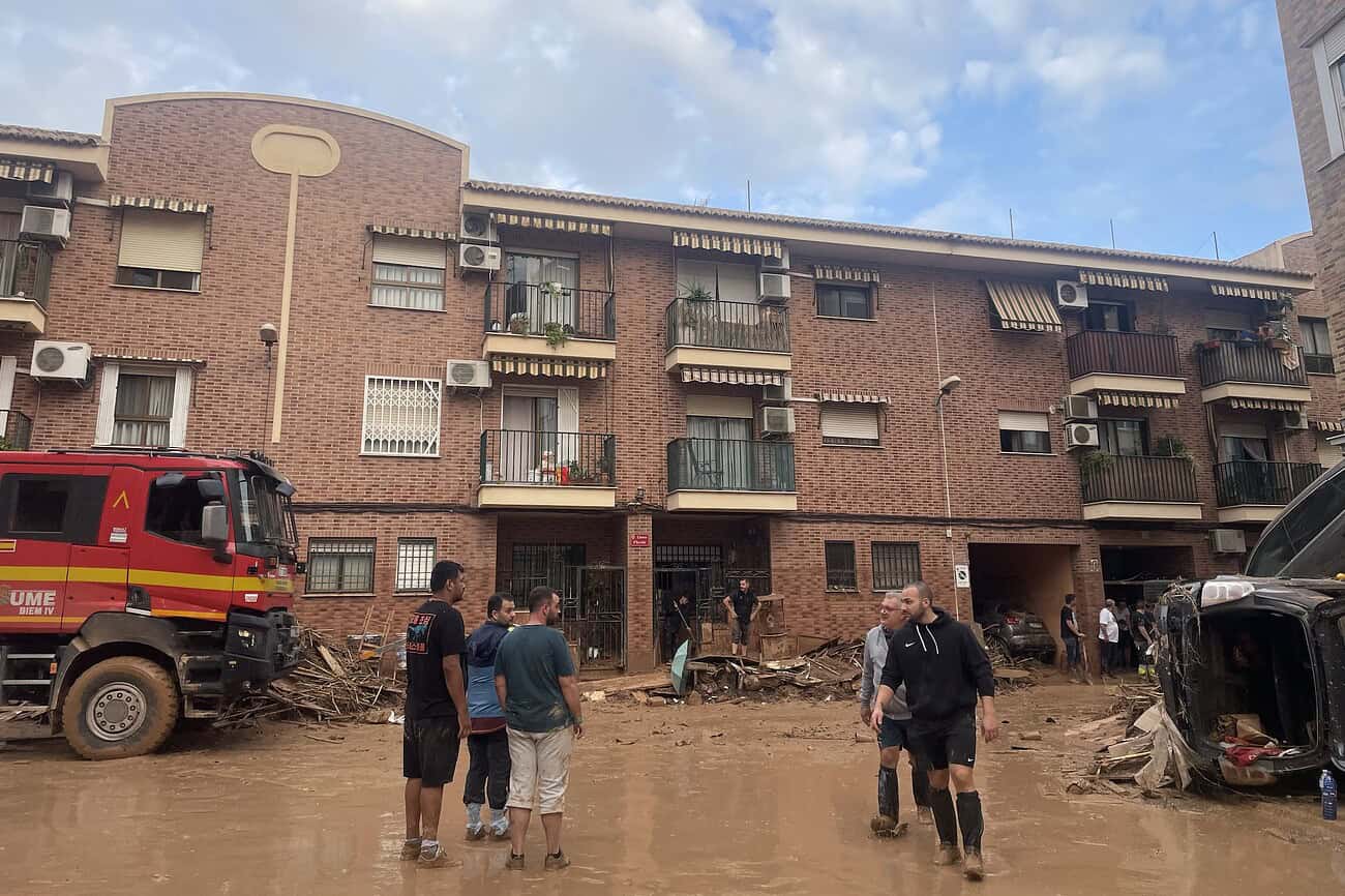 Réhabiter Valence un an après les inondations : le peuple va-t-il aider à sauver le peuple ? 4 Rues inondées à Valence après les inondations, habitants évaluant les dégâts et aidant à la reconstruction.