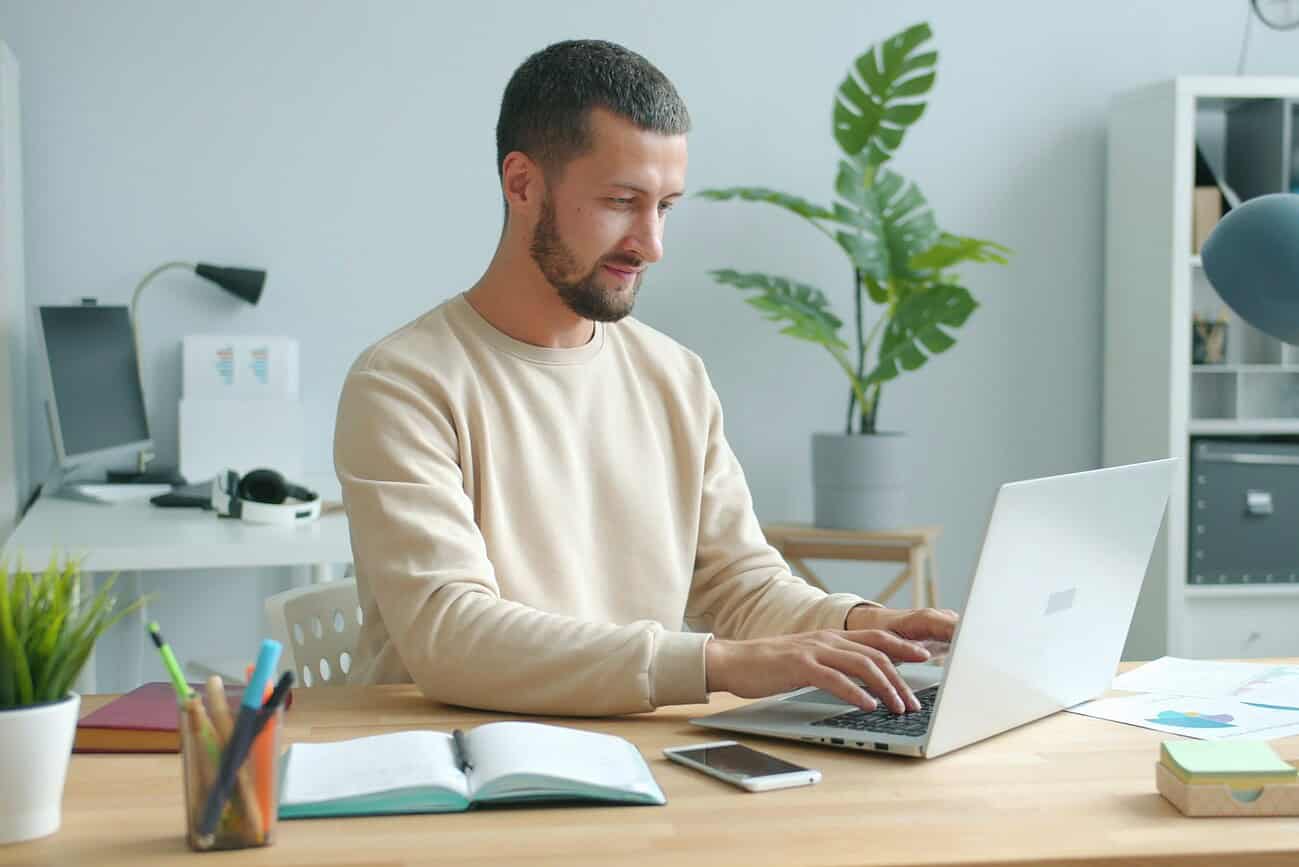 Homme utilisant un ordinateur portable pour gérer ses assurances en ligne, dans un environnement de bureau moderne et bien organisé, illustrant la simplicité de l'assurance pour expatriés.