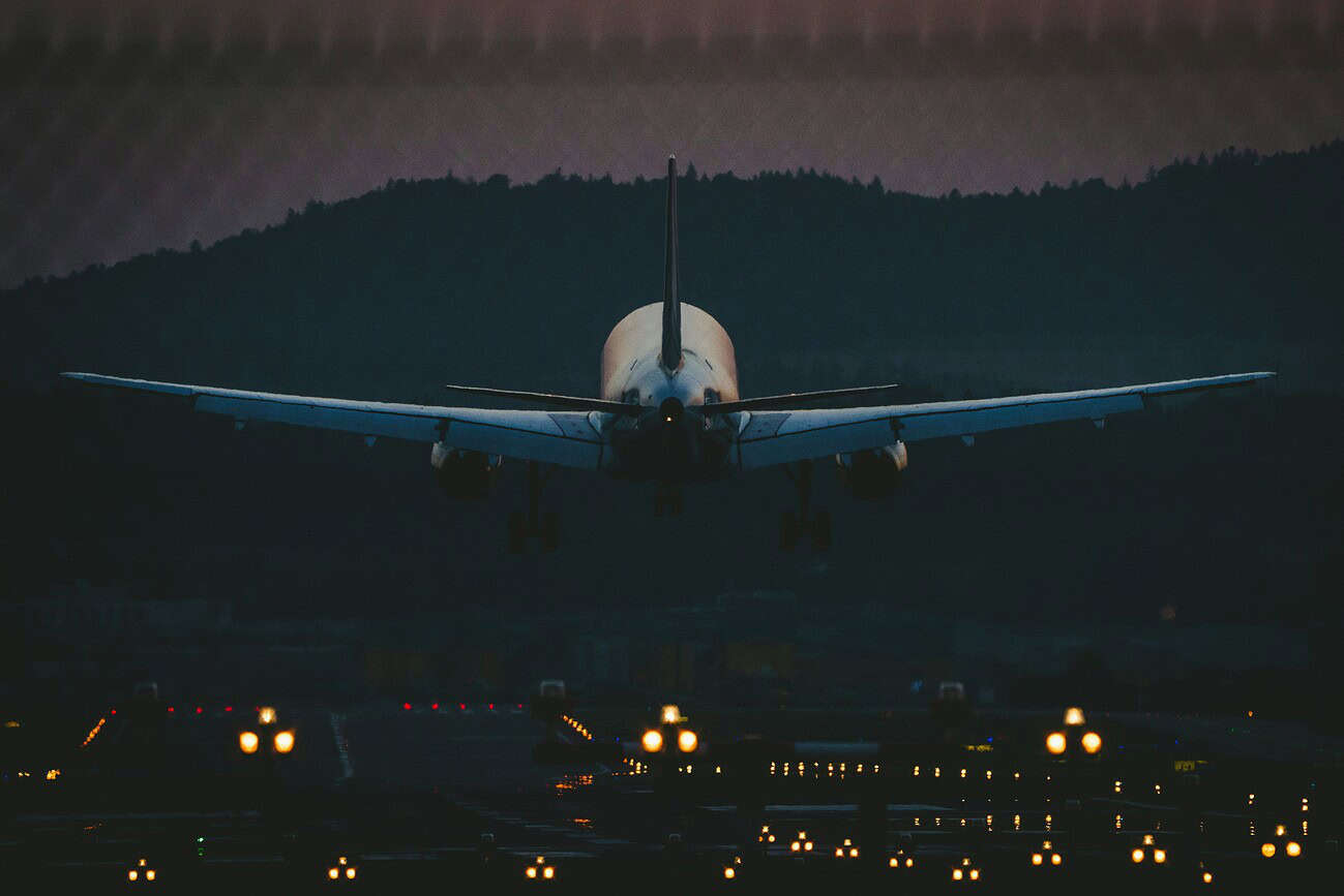 Avion prêt à décoller à l’aéroport de Barcelone, avec un paysage de montagnes en arrière-plan, illustrant l’investissement dans les vols nocturnes pour améliorer la connectivité.