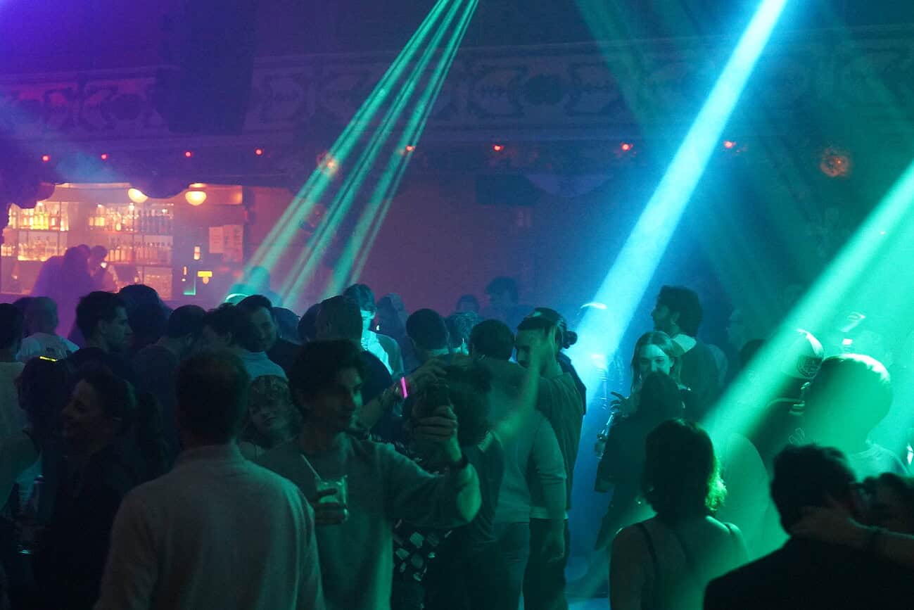 Bal masqué et feux d'artifice au Nouvel An à Barcelone, ambiance festive avec lumières colorées et foule joyeuse.