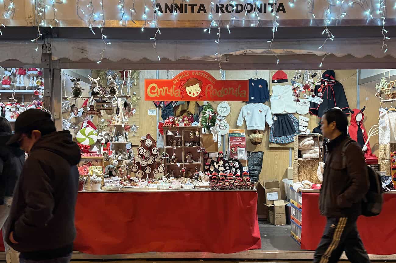 Les secrets des marchés de Noël à Barcelone, entre enchantement et survie 4 Vitrine d’un stand de marché de Noël à Barcelone, proposant des décorations festives, jouets et accessoires pour célébrer la saison hivernale.