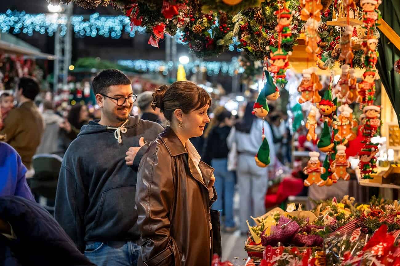 Noël en Catalogne : les pires cadeaux à ramener à votre famille en France 3 Une famille explore un marché de Noël en Catalogne, entourée de décorations festives et de stands colorés proposant des cadeaux traditionnels et artisanaux pour la saison des fêtes.
