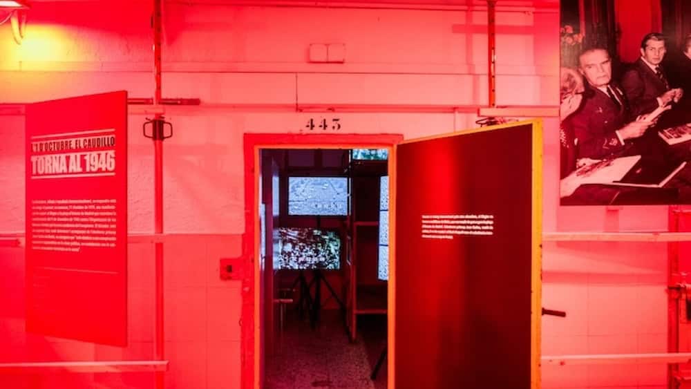 Une salle d'exposition rouge avec une porte ouverte menant à une pièce sombre, illustrant une activité culturelle ou historique à Barcelone durant le week-end du 19 au 21 décembre.