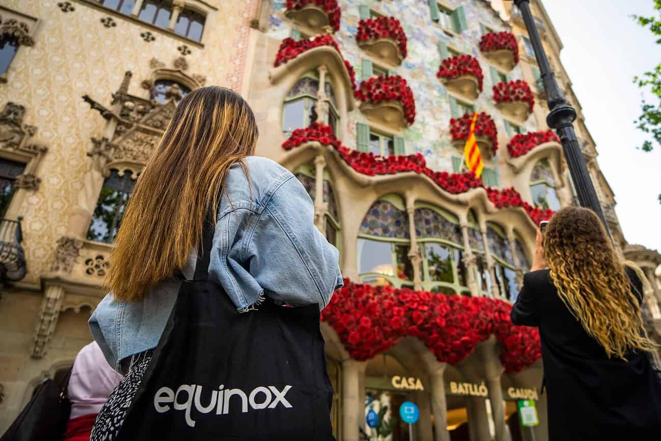 Deux femmes admirent la façade décorée de la Casa Batlló à Barcelone lors de la célébration de la Sant Jordi, avec des fleurs rouges et des drapeaux catalans.