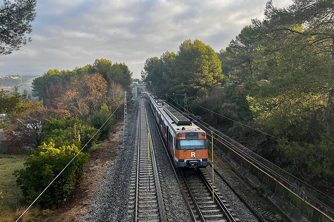 Train de banlieue en mouvement sur une voie ferrée entourée de végétation, illustrant la paralysie des transports en Catalogne due à la grève.