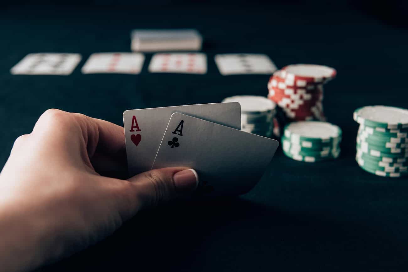 Pourquoi économiser à Barcelone est finalement plus difficile qu'à Paris 2 Joueur tenant deux cartes d'as, symbole de chance et stratégie dans le poker.