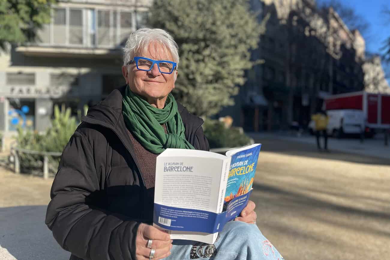 Pierre Lunel publie Le Roman de Barcelone, un hommage littéraire à la capitale catalane 8 Une femme âgée lit un livre intitulé "Le Roman de Barcelone" dans un parc urbain ensoleillé.