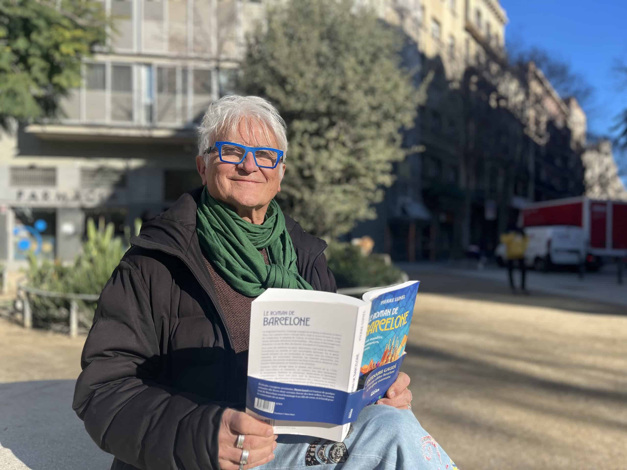 Une femme âgée lit un livre intitulé "Le Roman de Barcelone" dans un parc urbain ensoleillé.