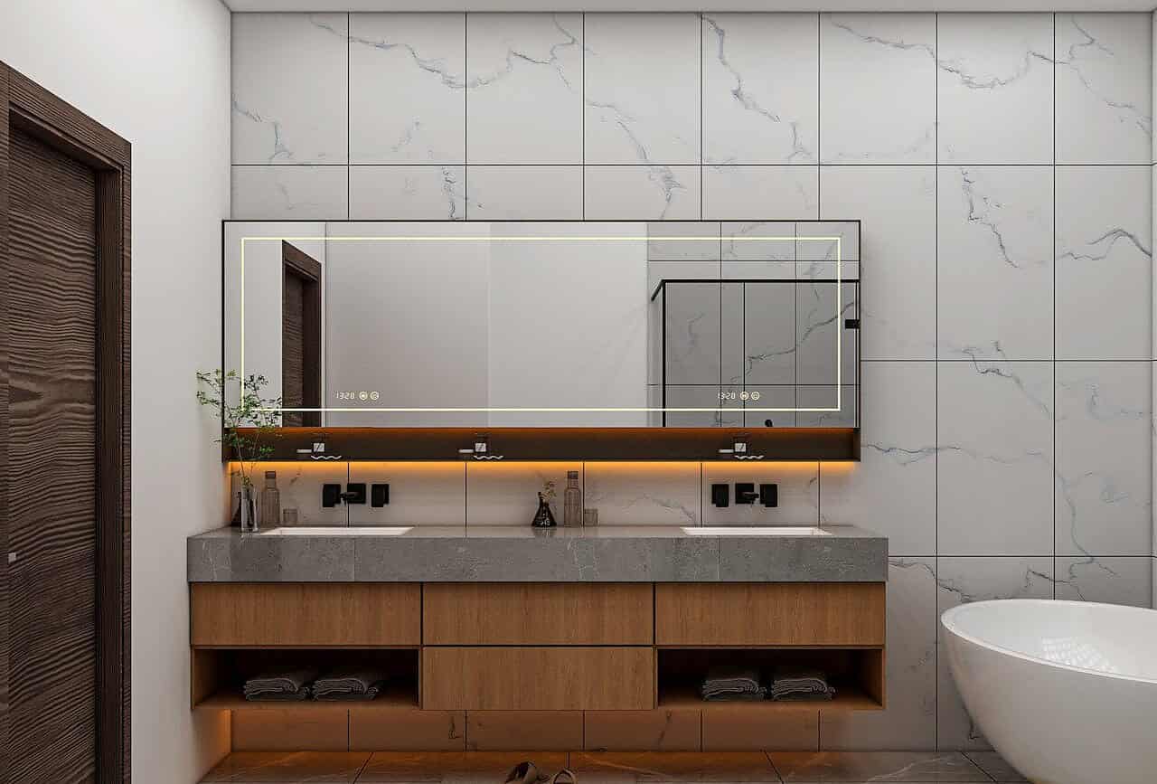 Pourquoi les transitions entre les matériaux sont-elles importantes dans les salles de bains ? 1 Balcon de salle de bain moderne avec miroir éclairé et meuble en bois, illustrant l'importance des transitions entre matériaux pour une esthétique harmonieuse et une durabilité accrue.