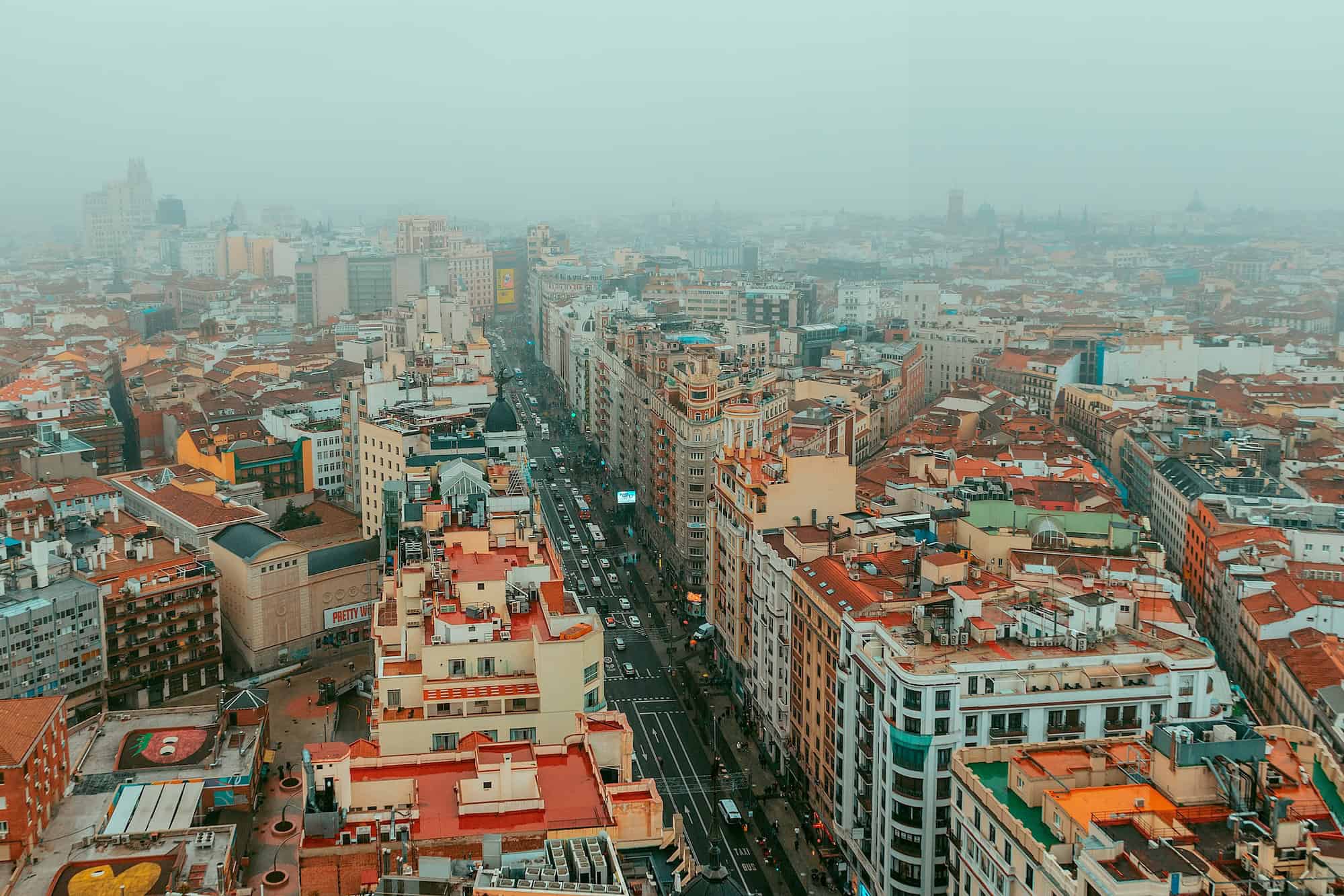 Vue panoramique d'une ville européenne avec architecture variée et ciel brumeux.