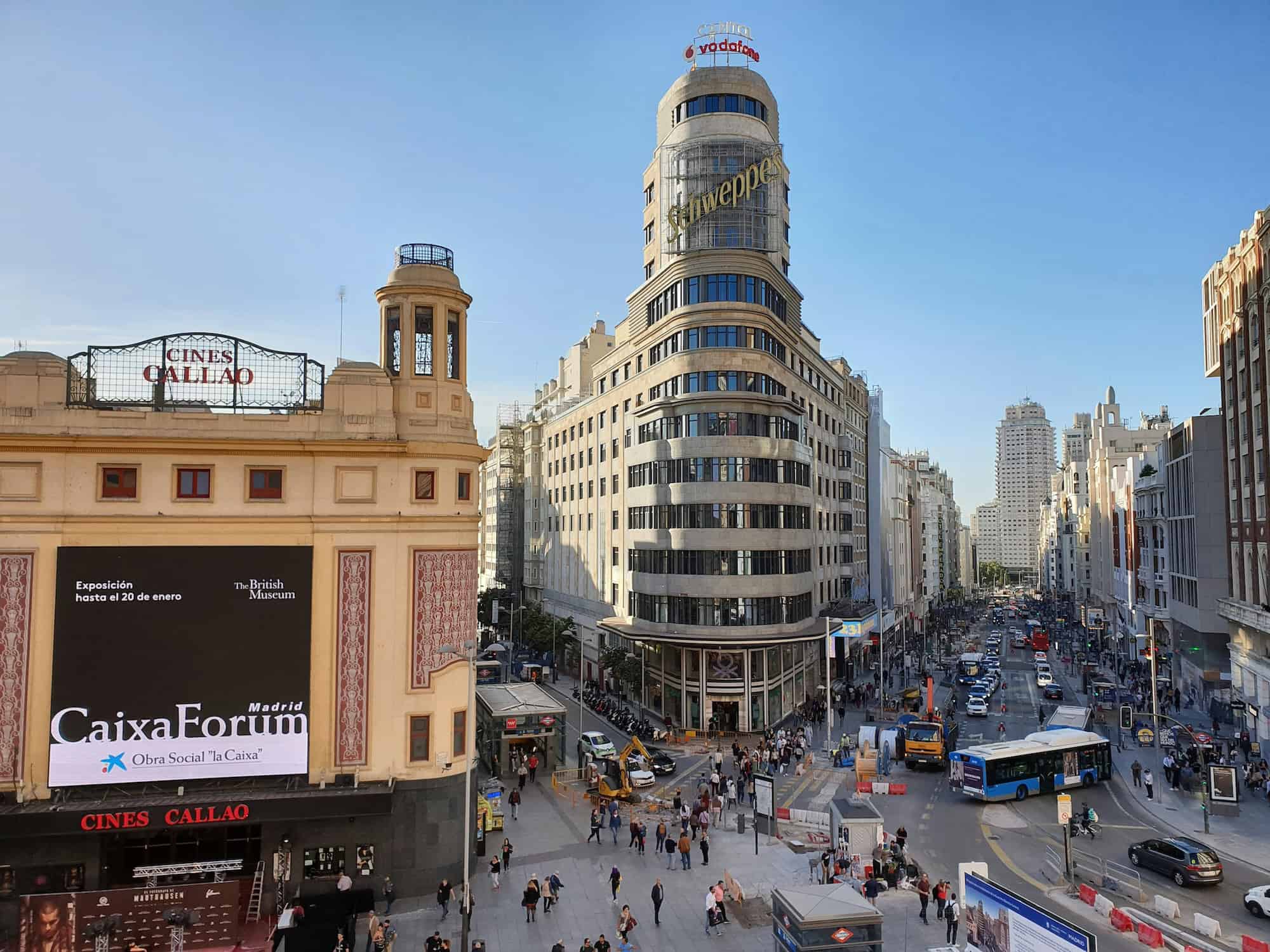 Que faire à Madrid le week-end du 9 au 11 octobre 1 Une vue dynamique du centre-ville de Madrid, mettant en valeur le bâtiment emblématique Schweppes et l'animation urbaine avec des piétons et des véhicules.