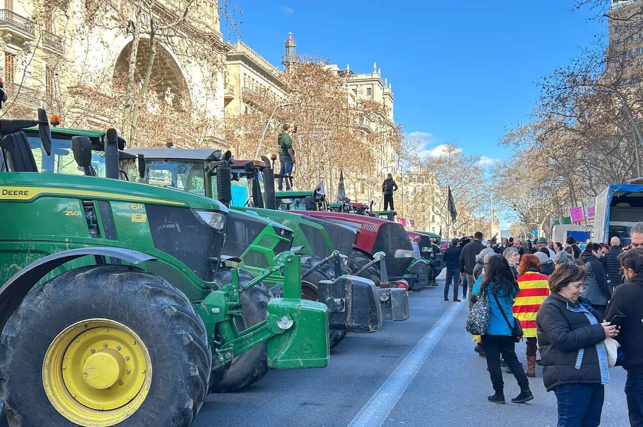 Tracteurs agricoles en protestation lors d'une manifestation à Barcelone, avec des agriculteurs et des citoyens rassemblés pour soutenir la cause.