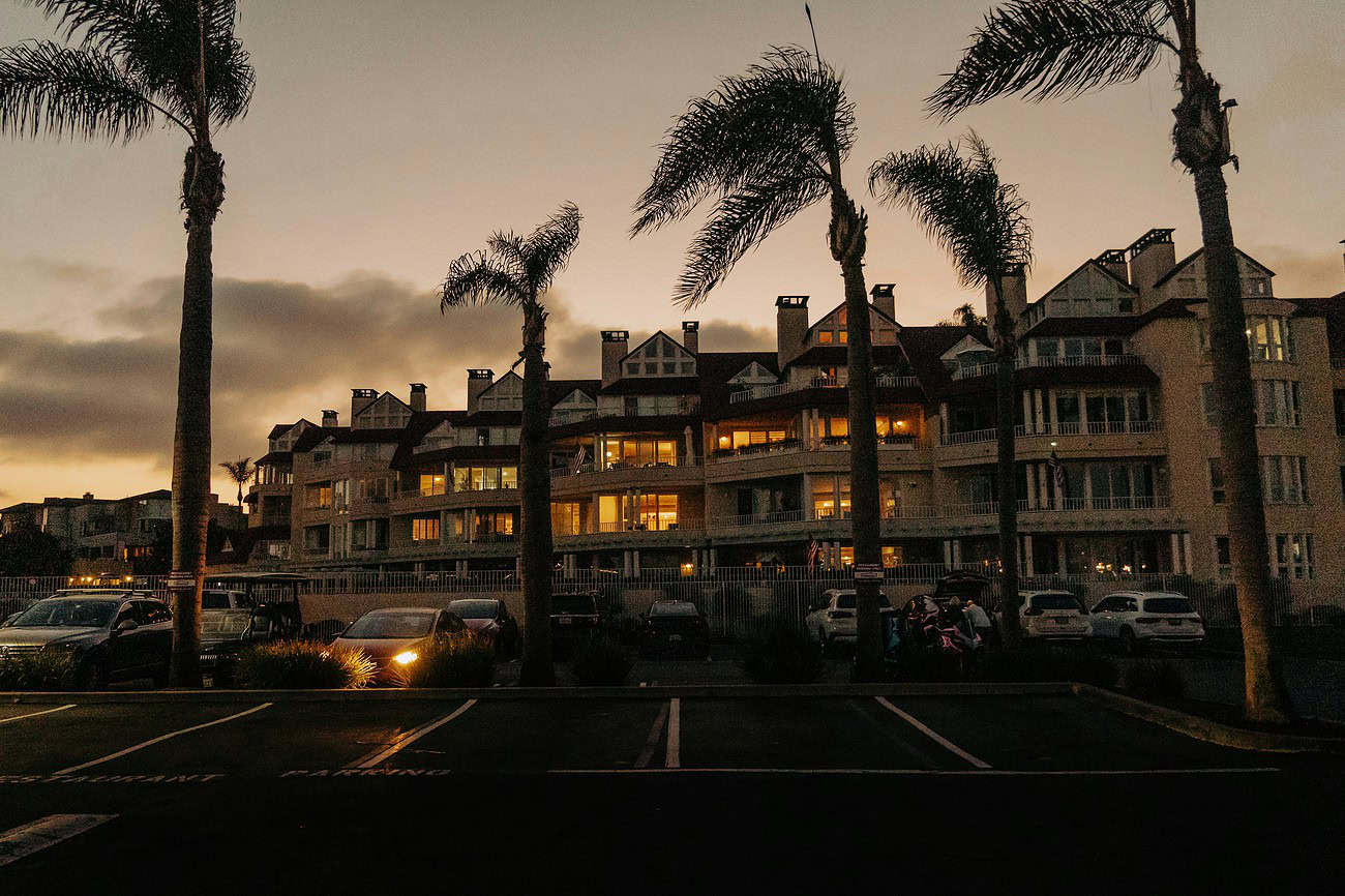 La révolution numérique silencieuse derrière les locations de vacances d’aujourd’hui 2 Vue d’un complexe résidentiel en bord de mer avec palmiers, au coucher du soleil, illustrant la révolution numérique dans la location de vacances.