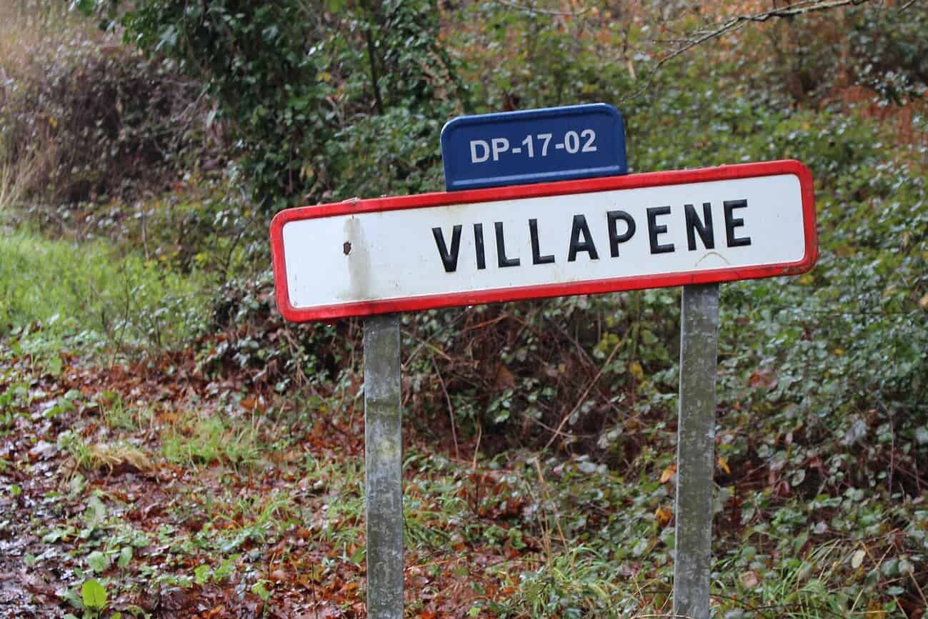 Les 10 villages aux noms les plus bizarres d’Espagne 5 Panneau indiquant le village de Villapene, un lieu connu pour son nom original en Espagne, entouré de nature verdoyante.