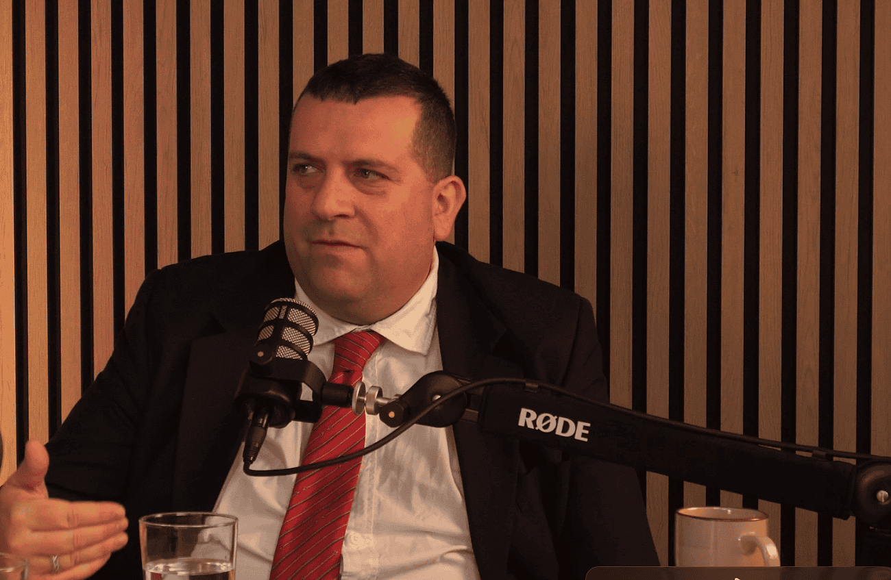 Homme en costume lors d'une interview, parlant de l'achat immobilier en Espagne et des risques liés aux paiements au noir.