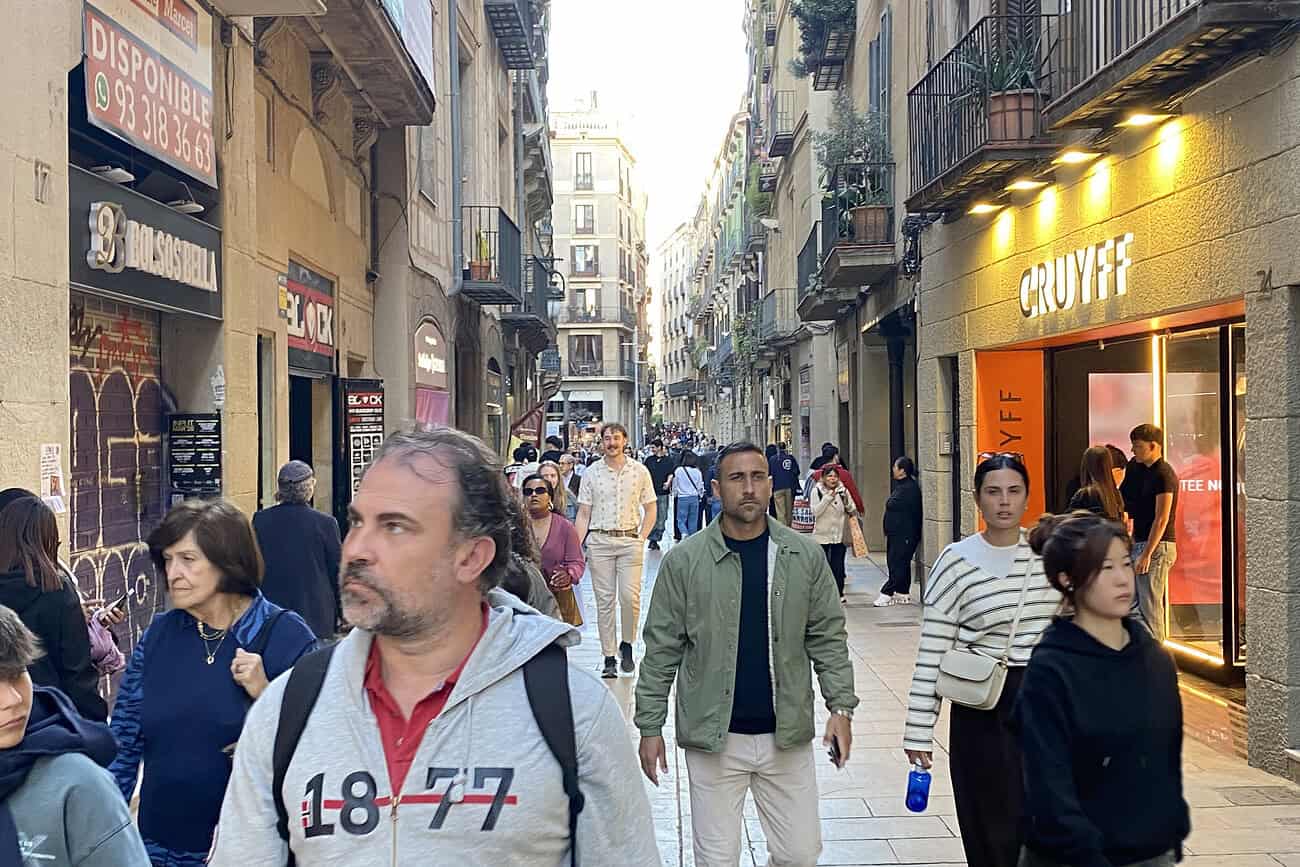 Y a-t-il trop de commerces à Barcelone ? 2 Vue animée d'une rue piétonne à Barcelone avec des passants divers, boutiques et cafés, illustrant la vie commerciale dynamique dans la ville.