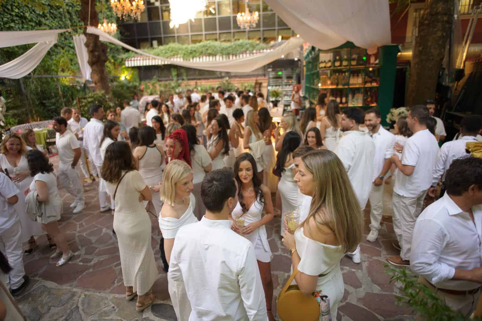 Bal populaire en plein air à Madrid lors d'une fête estivale. Des personnes en tenue blanche profitent d'une ambiance conviviale avec musique et décoration festive.