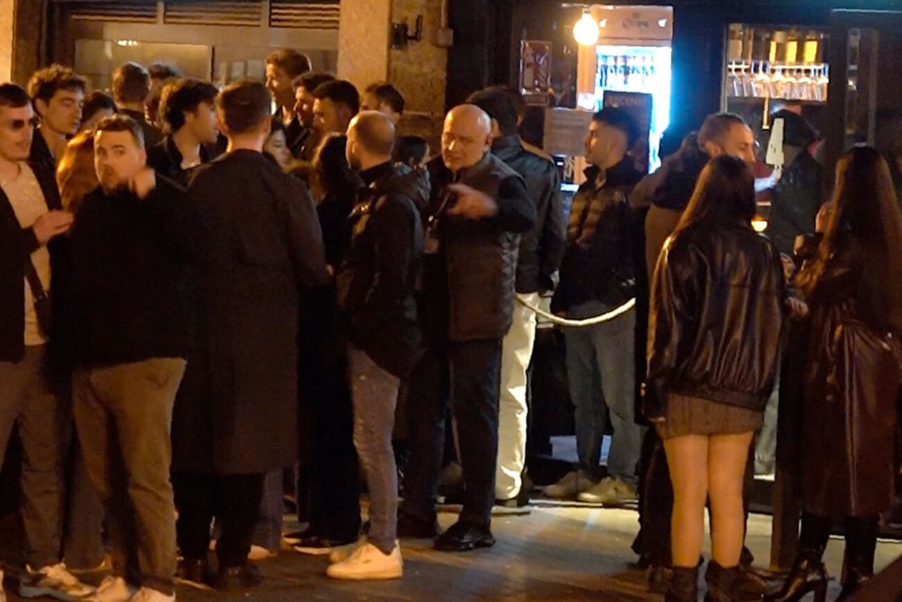Groupe de jeunes et d'adultes rassemblés dans une rue animée de Barcelone la nuit, illustrant l'ambiance festive et les défis liés à la surpopulation lors des événements.