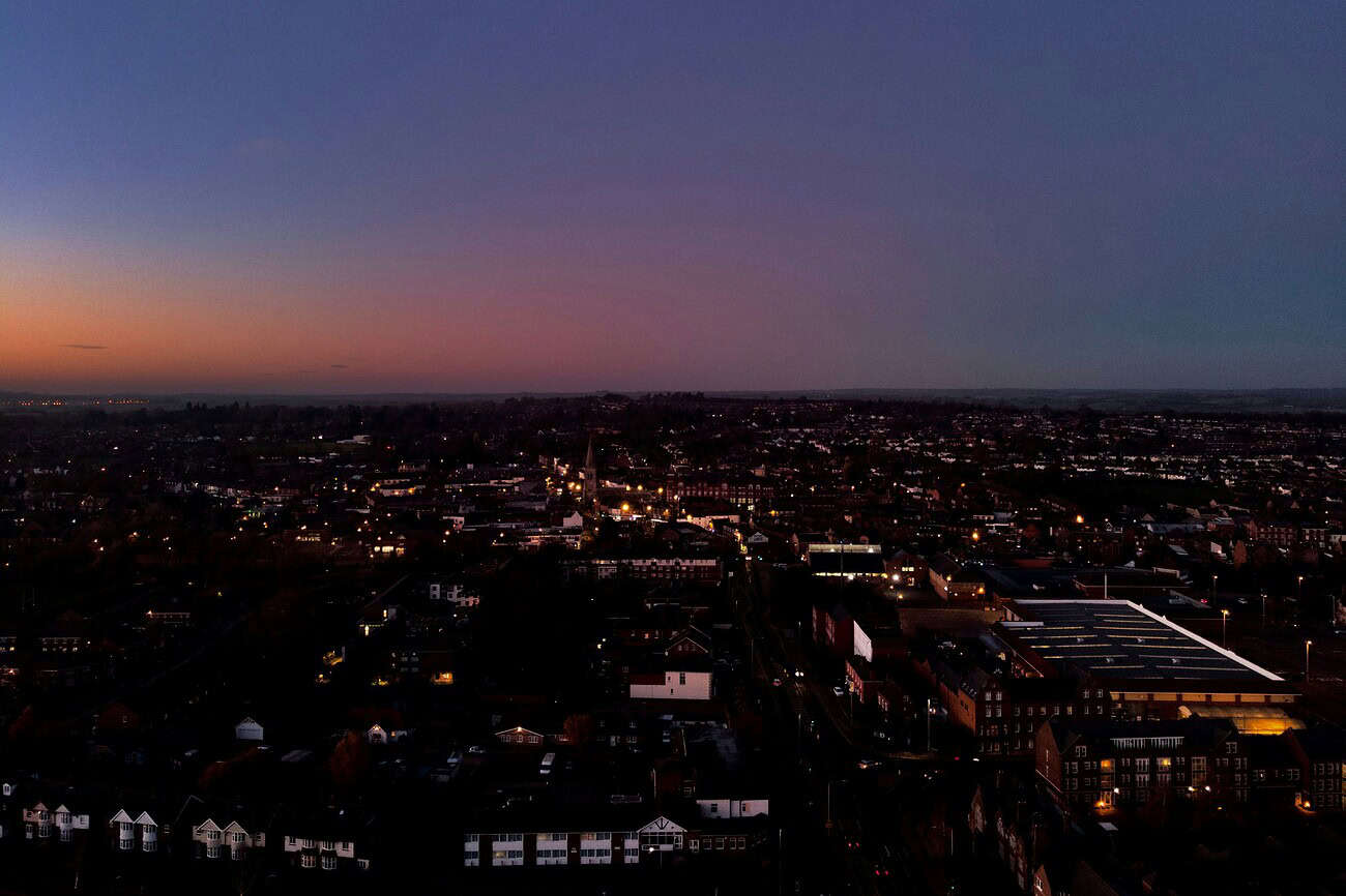 Espagne insomniaque : nuits blanches au pays de la sieste 3 Vue panoramique d'une ville espagnole la nuit, avec un ciel étoilé et des lumières urbaines, illustrant la tranquillité nocturne et le contraste entre la ville et le ciel.
