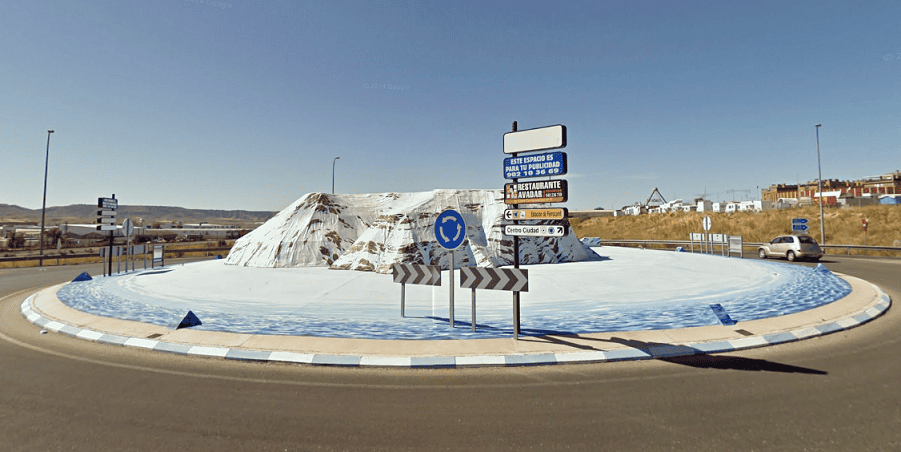 Rond-point original en Espagne avec sculpture de glace et signalisation, attirant l'attention des conducteurs et touristes dans un paysage désertique.