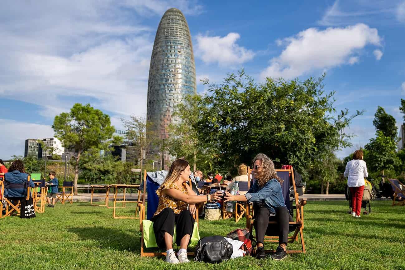 Balade conviviale entre amis dans un parc urbain de Barcelone avec vue sur la Tour Agbar, favorisant le bien-être et la détente pour les expatriés français.