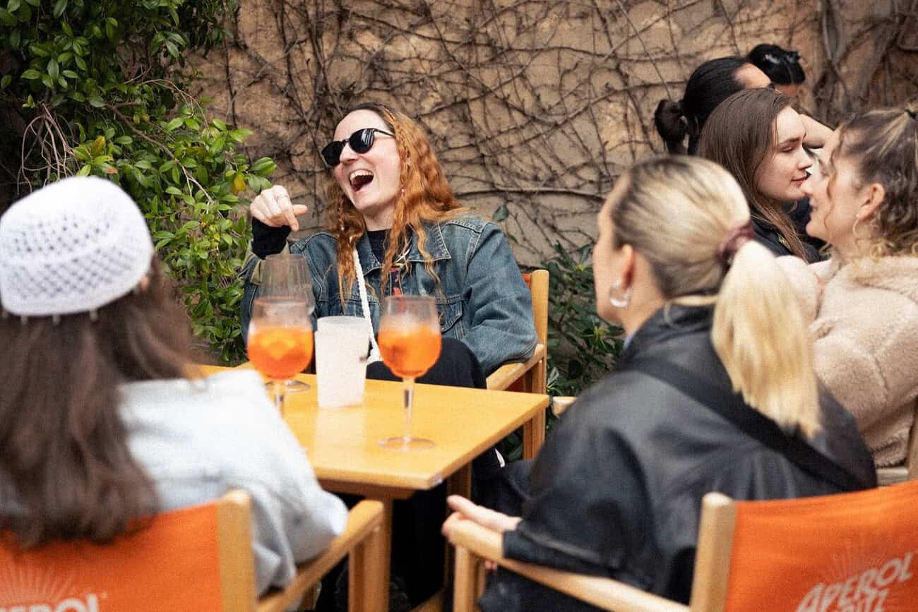 Groupe d'amis profitant d'une après-midi ensoleillée dans un café en terrasse à Barcelone, dégustant des boissons rafraîchissantes et partageant un moment convivial.