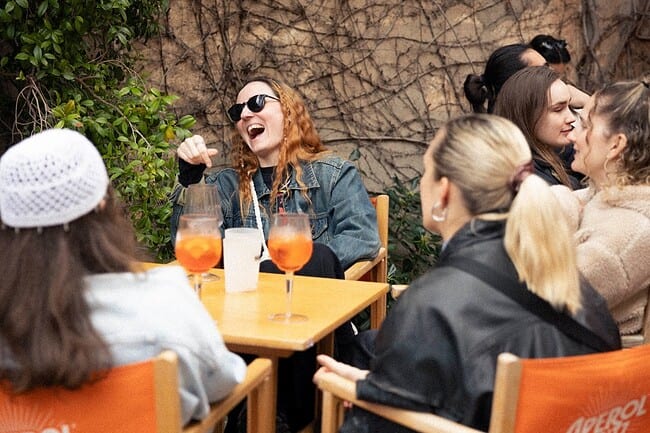 Groupe d'amis profitant d'une après-midi ensoleillée dans un café en terrasse à Barcelone, dégustant des boissons rafraîchissantes et partageant un moment convivial.